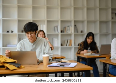 Young Asian male student using laptop preparing for exams in the library campus - Powered by Shutterstock