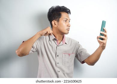 Young Asian Man Angry, Frustrated And Furious With His Phone, Angry With Customer Service Over White Background.