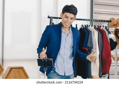 Young Asian Man Blogger Is Trying On Clothes While Broadcasting A Video For Selling Clothes Online.