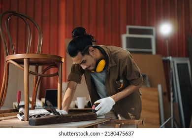 Young Asian Man Carpenter Uses A Tape Measure To Measure Chair On The Workbench In Woodcraft Carpentry Workshop. 