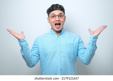 Young Asian Man Celebrating Crazy And Amazed For Success With Arms Raised And Open Eyes Screaming Excited Over White Background. Winner Concept