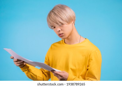 Young Asian Man Checks Documents, Utility Bills, Report. Guy Isolated On Yellow Background. 