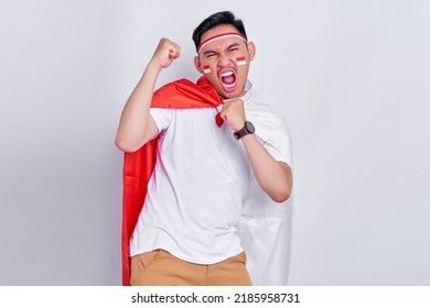 Young Asian man clenched both fist to celebrate Indonesia independence day on August 17, looking at camera with confident and excited expression isolated on white background