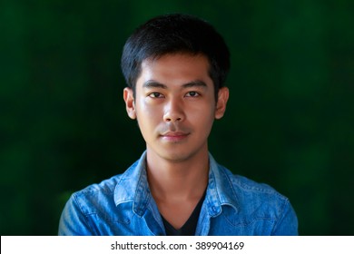 Young Asian Man Close Up Head Shot On Deep Green Background