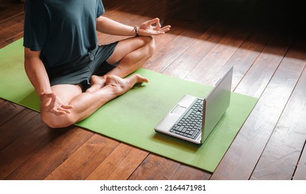 Young Asian Man  Coach Internet Video Online Training Yoga Instructor Modern Laptop Screen Meditate Sukhasana Posture Relax Breathe Easy Seat Pose Gym Healthy Lifestyle At Home Concept.