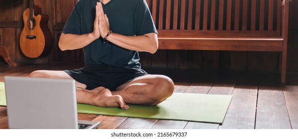 Young Asian Man  Coach Internet Video Online Training Yoga Instructor Modern Laptop Screen Meditate Sukhasana Posture Relax Breathe Easy Seat Pose Gym Healthy Lifestyle At Home Concept.