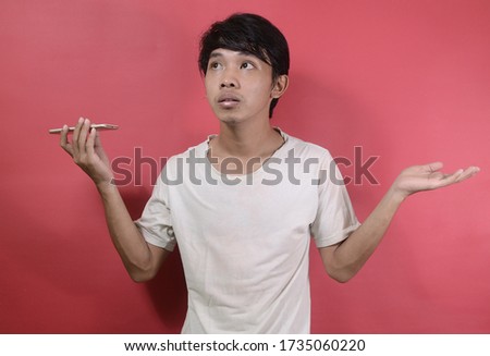 Young asian man in a confused expression. Asian men wearing white t shirts isolated on a red background