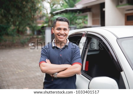young asian man crossed arm standing in front of his car. taxi driver