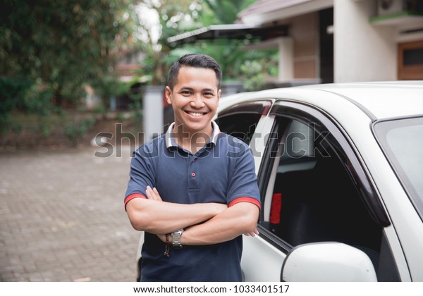 young asian man crossed arm standing in front of\
his car. taxi driver