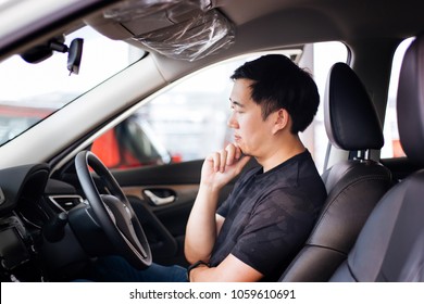 Young Asian Man As A Customer Sitting Inside A Car Thinking And Considering To Buy Automobile Or Car Insurance