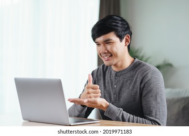 Young Asian Man Deaf Disabled Using Laptop Computer For Online Video Conference Call Learning And Communicating In Sign Language.
