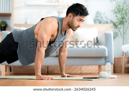Young asian man doing pushup exercise in living room at home with determination, man training on yoga mat, bodybuilding strength and fitness for healthy lifestyle, workout routine, self-care.