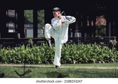 Young Asian man doing Tai Chi sword in the park. - Powered by Shutterstock