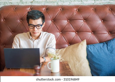 Young Asian Man Drinking Coffee In Cafe And Using Laptop Computer, Art Coffe Shop