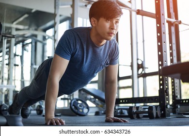 Young Asian Man Exercising In The Fitness Gym With Flare Light
