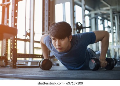 Young Asian Man Exercising In The Fitness Gym With Flare Light
