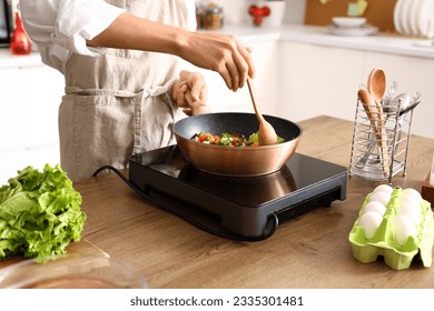 Young Asian man frying vegetables in kitchen, closeup