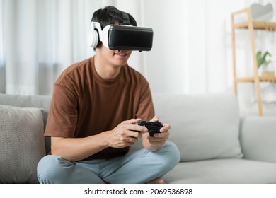 Young Asian Man Gamer Wearing Virtual Reality Touching Air During The VR Experience  Future Home Technology Player Hobby Playful Enjoyment Concept