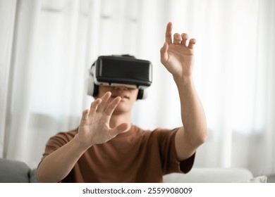 Young Asian man gamer wearing virtual reality touching air during the VR experience  Future home technology player hobby playful enjoyment concept