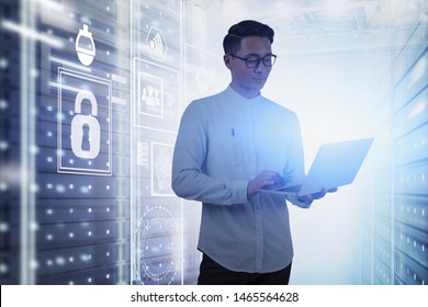 Young Asian Man In Glasses Using Laptop Computer In Server Room With Double Exposure Of HUD Cyber Security Interface. Concept Of Data Protection. Toned Image