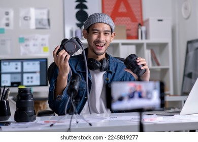 Young Asian man graphic designer blogger influencer filming teaching camera tutorial while looking at camera shooting education tutorial vlog training filming video course for social media at studio 