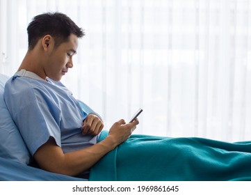 Young Asian man had accident get broken arm use splint to recover it. Lying on bed look at mobile phone reading message who care his sickness and want to encourage him to get well soon - Powered by Shutterstock