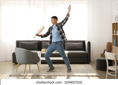 Young Asian Man Having Fun While Doing Chores At Home