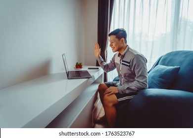 Young Asian Man Having Video Conference Meeting With Boxer Shorts On Sofa At Home During Quarantine.