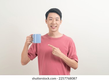 young Asian man holding coffee cup with smiling face on white background - Powered by Shutterstock