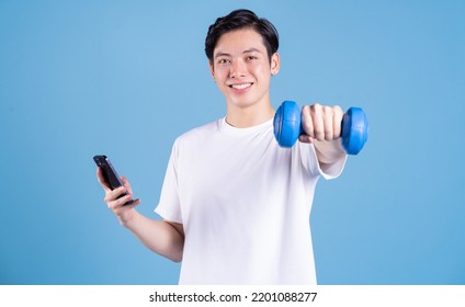 Young Asian man holding dumbbell on background - Powered by Shutterstock