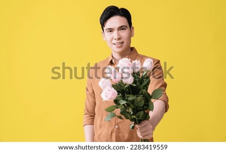 Young Asian man holding flower on background