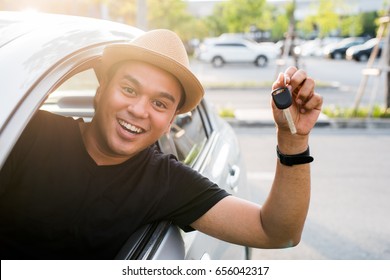 Young asian man holding key while sitting in new car