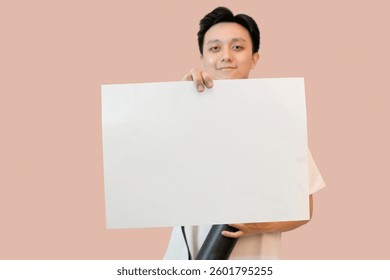 young asian man holding project paper mockup in pink isolated background