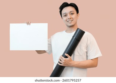 young asian man holding project paper mockup in pink isolated background