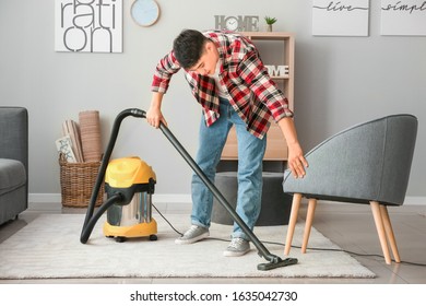 Young Asian Man Hoovering Floor At Home