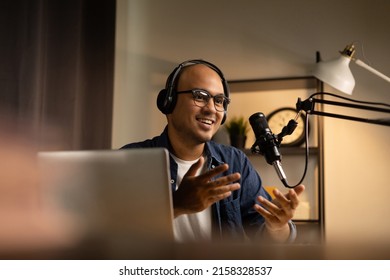 Young asian man host streaming podcast with condenser microphone work on laptop at small broadcast home studio. Content creator blogger recording voice over radio interview guest conversation - Shutterstock ID 2158328537