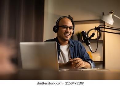 Young asian man host streaming podcast with condenser microphone work on laptop at small broadcast home studio. Content creator blogger recording voice over radio interview guest conversation - Shutterstock ID 2158493109
