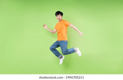 young asian man jumping , isolated on green background