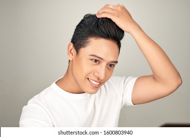 Young Asian Man Is Lokking In Mirror And Touching His Hair On White Background