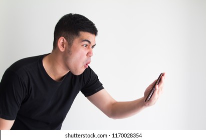 Young Asian Man Looking At Phone And Feels Shock And Surprise With Overly Face Expression.