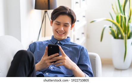 Young Asian Man Lying On Sofa And Using Phone
