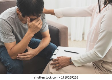Young Asian Man, Male Suffers From A Mental Who Needs To Therapy With A Psychologist While Sitting On Couch To Consult, Psychiatrist Has Encouragement The Patient By Touching To Make His Feel Relaxed.