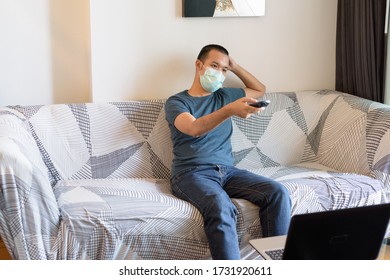 Young Asian Man With Mask Watching Tv At Home Under Quarantine