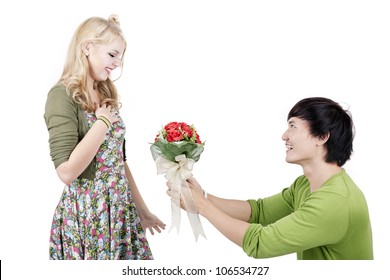 Young Asian Man On Knees Giving Woman Bouquet Of Flowers.