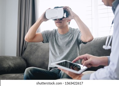 Young Asian Man Patient Using Virtual Reality Glasses To See Technology To Examination Physical Body Patient While Doctor Explains, 3D Gadget Technology, VR AR Glasses.