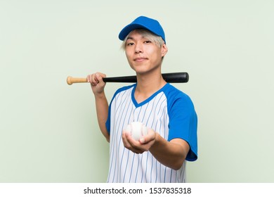 Young Asian Man Playing Baseball Over Isolated Green Background