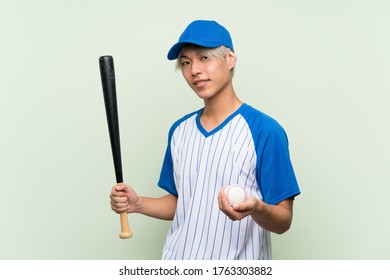 Young Asian Man Playing Baseball Over Isolated Green Background