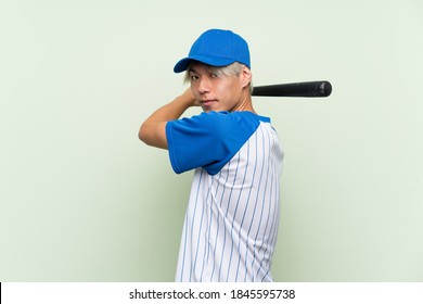 Young Asian Man Playing Baseball Over Isolated Green Background