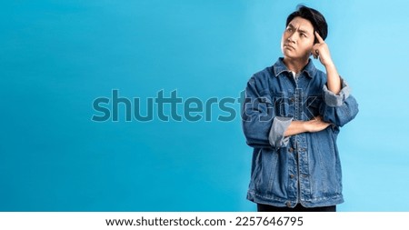 Young asian man posing on a blue background