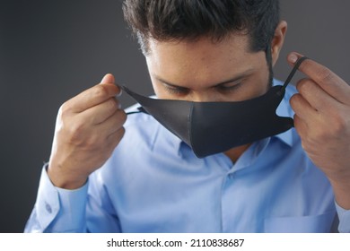 young asian man putting surgical face mask indoor  - Shutterstock ID 2110838687